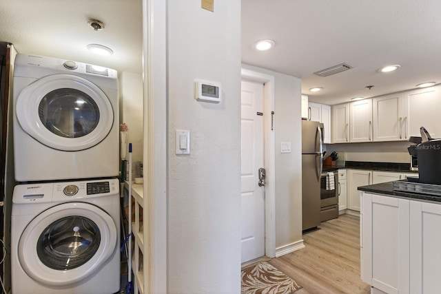 clothes washing area featuring stacked washer and dryer and light wood-type flooring