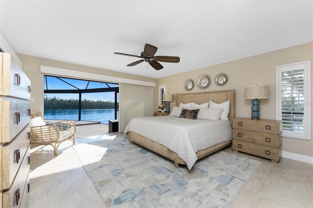 bedroom featuring multiple windows, a water view, access to outside, and ceiling fan