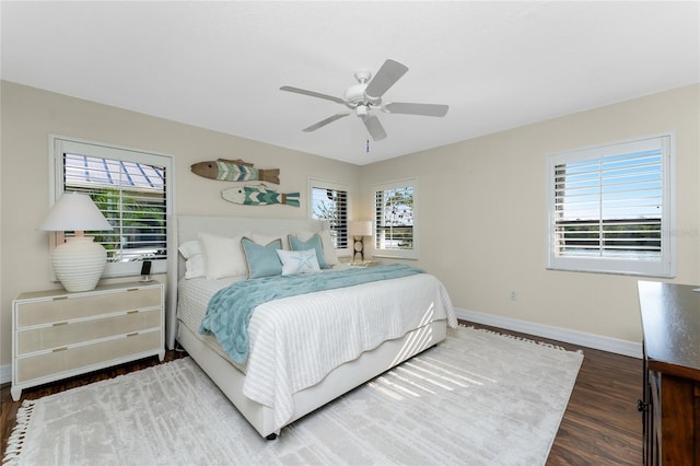 bedroom with multiple windows, dark hardwood / wood-style floors, and ceiling fan