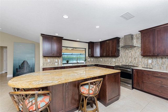 kitchen featuring a breakfast bar, stainless steel range with electric cooktop, tasteful backsplash, a kitchen island, and wall chimney range hood