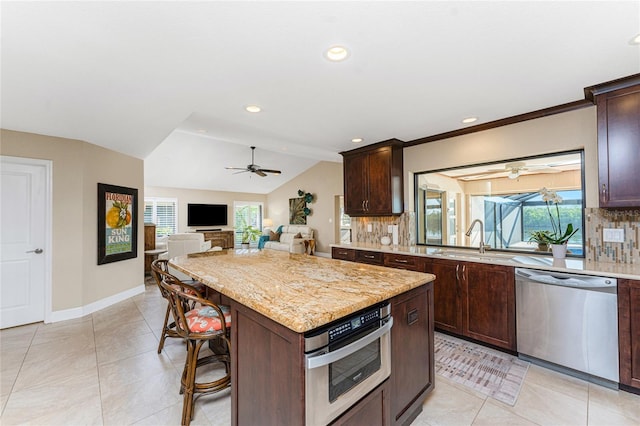 kitchen featuring sink, a breakfast bar area, appliances with stainless steel finishes, a kitchen island, and backsplash