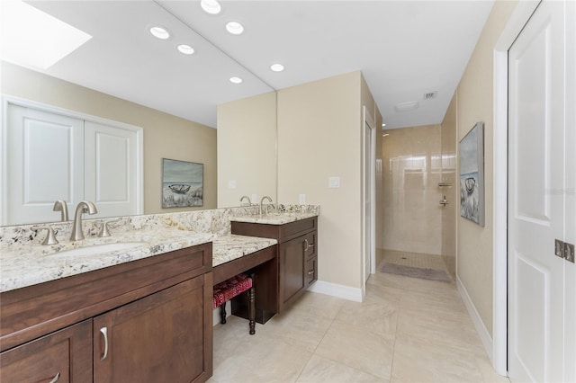 bathroom with vanity, a skylight, and a tile shower