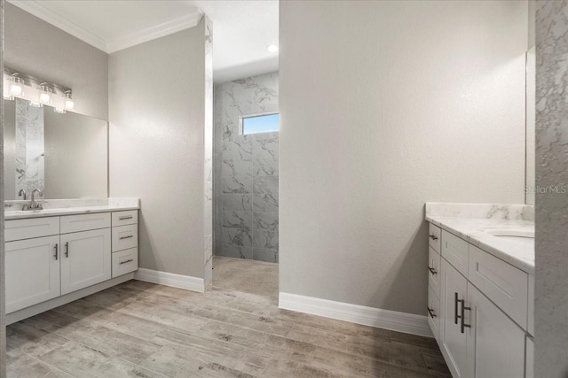 bathroom with vanity, wood-type flooring, ornamental molding, and a tile shower