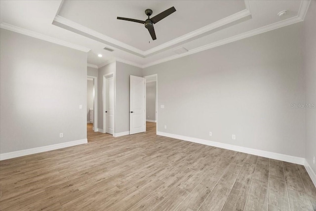 empty room with ornamental molding, ceiling fan, light hardwood / wood-style floors, and a tray ceiling