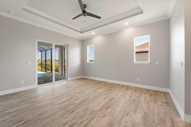 unfurnished room featuring ornamental molding, ceiling fan, light wood-type flooring, and a tray ceiling