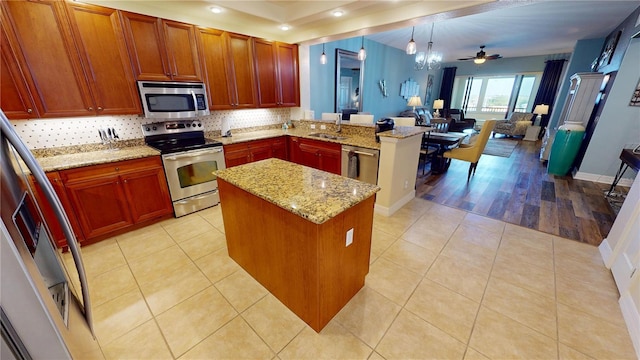 kitchen featuring a kitchen island, light tile patterned flooring, kitchen peninsula, and appliances with stainless steel finishes