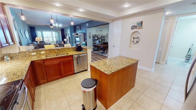 kitchen featuring a kitchen island, decorative light fixtures, sink, stainless steel appliances, and light stone countertops