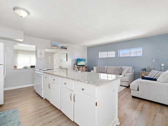 kitchen with white appliances, light hardwood / wood-style floors, a kitchen island, and white cabinets