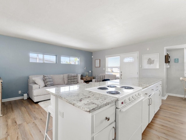 kitchen with electric stove, light stone counters, white cabinetry, and light hardwood / wood-style flooring