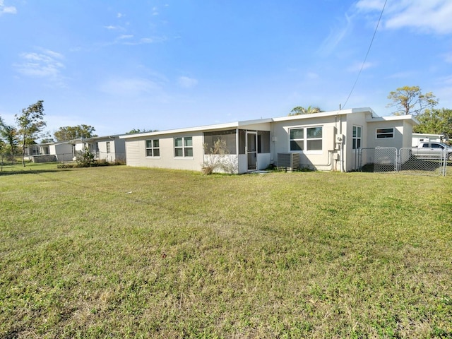 rear view of house with central AC and a lawn