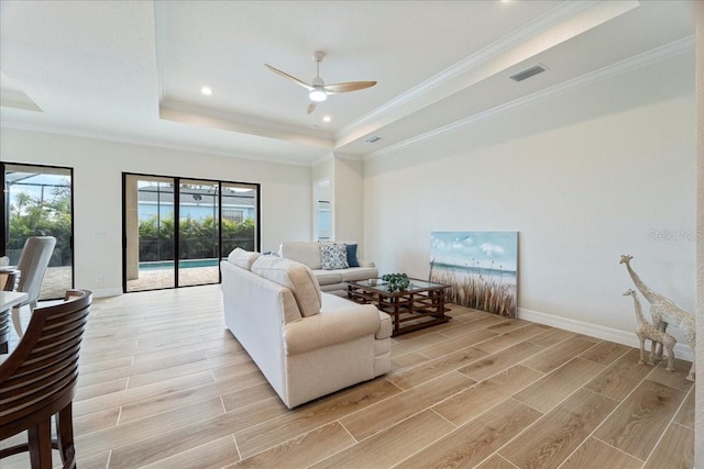 living room featuring ceiling fan, ornamental molding, and a tray ceiling