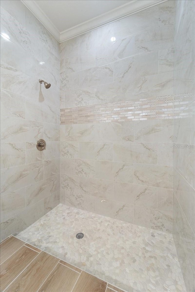 bathroom featuring ornamental molding, hardwood / wood-style floors, and a tile shower