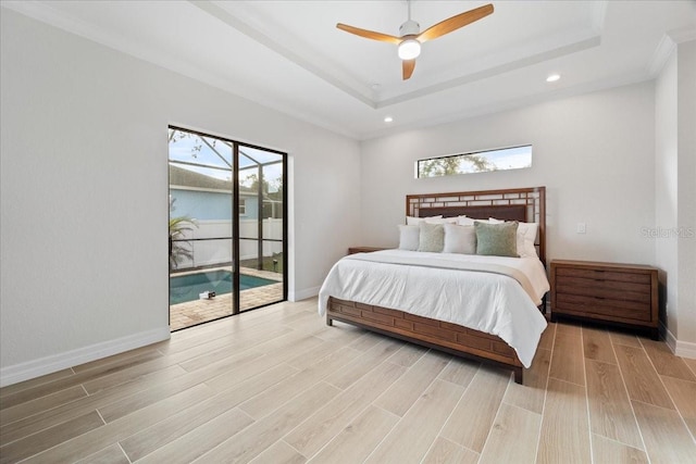 bedroom with ceiling fan, access to exterior, and a raised ceiling