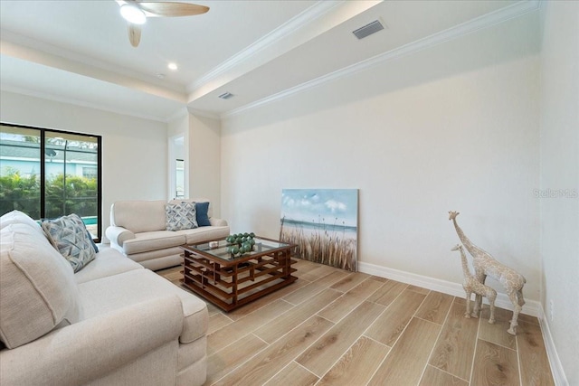 living room featuring crown molding, ceiling fan, and a raised ceiling