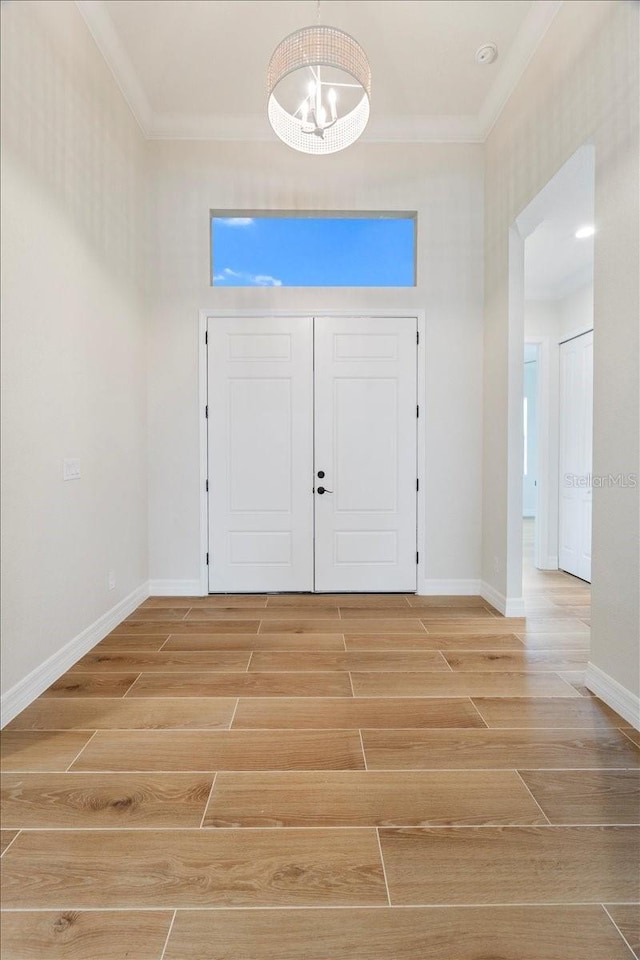 foyer entrance with crown molding and a chandelier