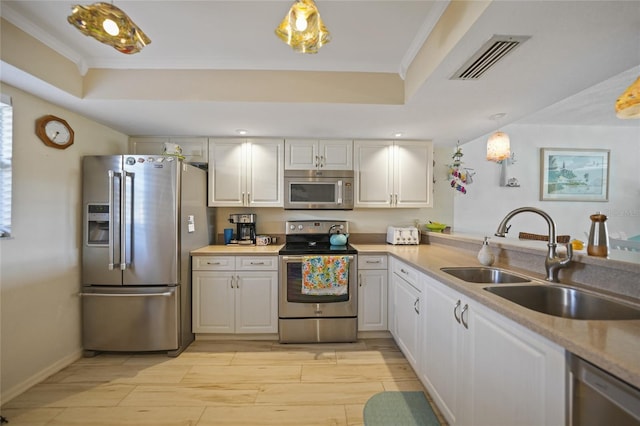 kitchen featuring a raised ceiling, white cabinetry, appliances with stainless steel finishes, and sink