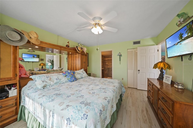 bedroom with ceiling fan, ensuite bath, and light hardwood / wood-style flooring