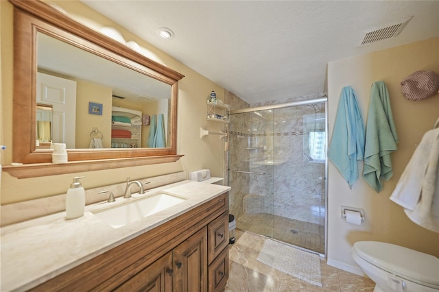 bathroom featuring vanity, a shower with shower door, and toilet