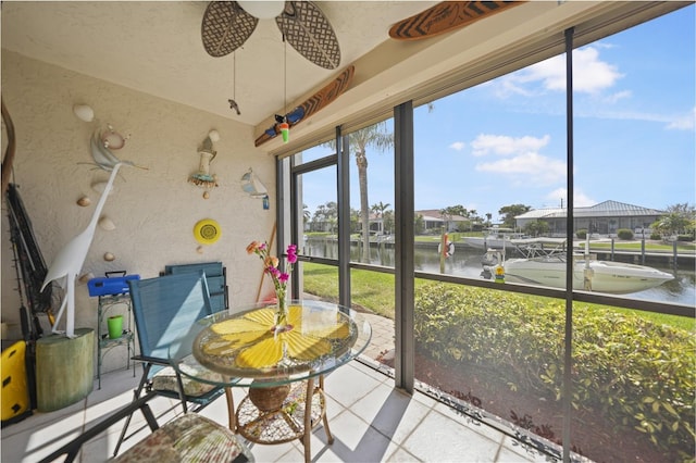 sunroom / solarium featuring a water view and ceiling fan