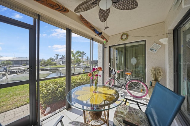 sunroom featuring ceiling fan and a water view