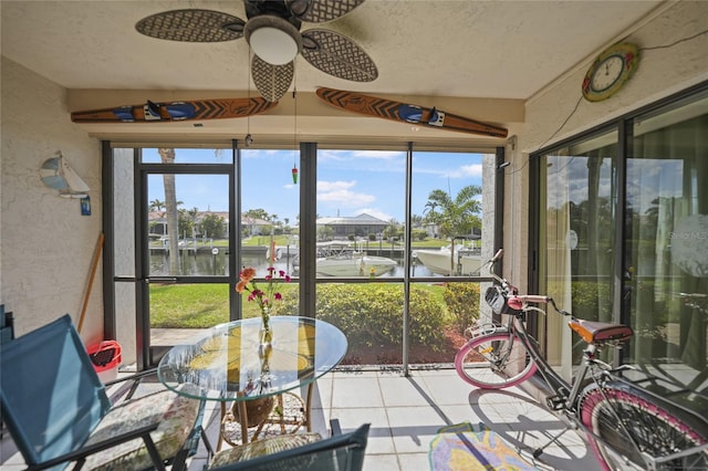 sunroom / solarium featuring ceiling fan and a water view