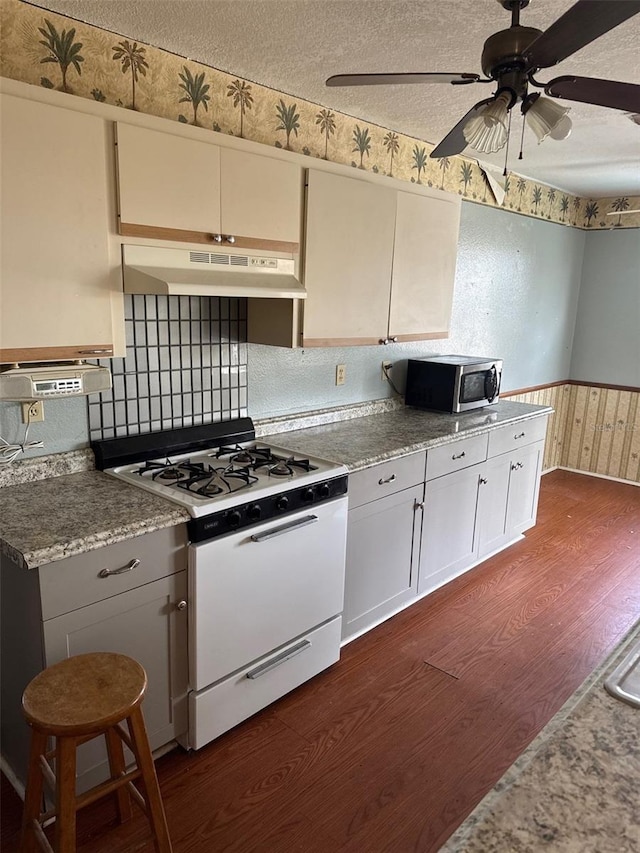 kitchen with dark wood-type flooring, white gas stove, white cabinetry, a textured ceiling, and ceiling fan