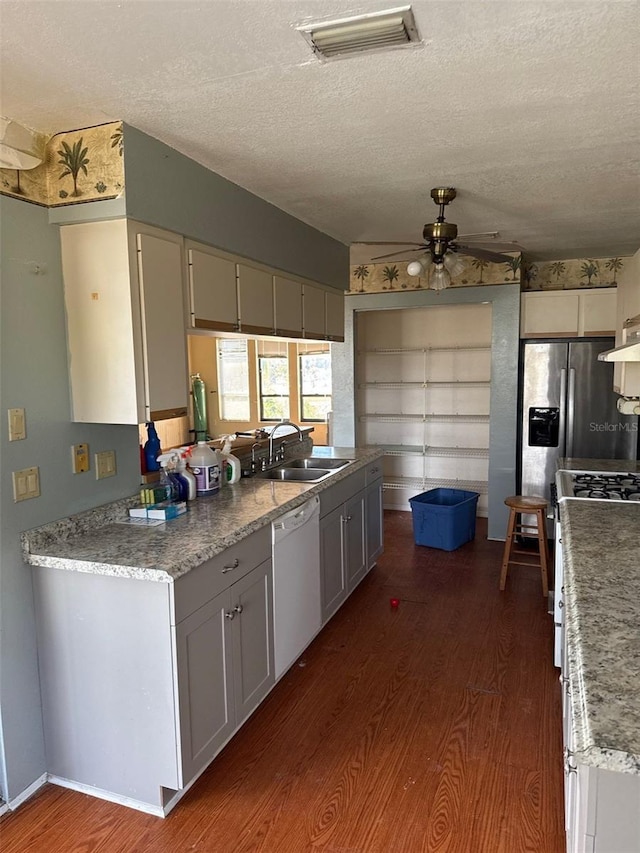 kitchen with white dishwasher, sink, dark hardwood / wood-style flooring, and a textured ceiling