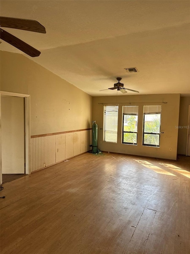 spare room featuring wood-type flooring, vaulted ceiling, a textured ceiling, and ceiling fan