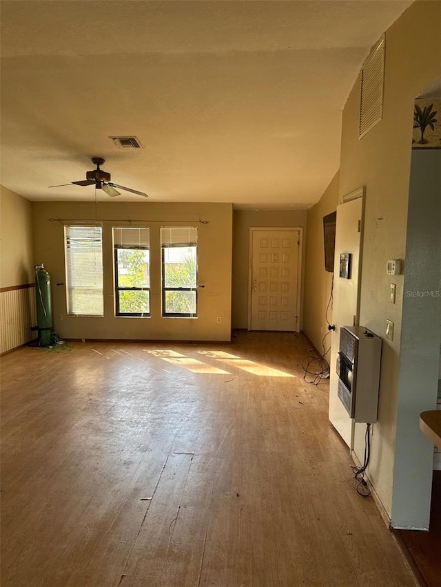 unfurnished living room featuring ceiling fan, heating unit, and light wood-type flooring