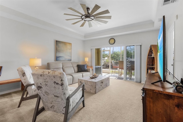 living room with light carpet, a tray ceiling, and ceiling fan