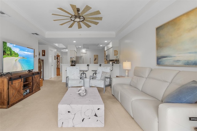 living room with ornamental molding, light colored carpet, and a tray ceiling