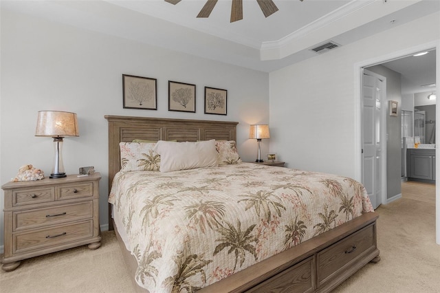 carpeted bedroom with crown molding, connected bathroom, ceiling fan, and a tray ceiling