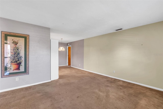 carpeted empty room with a chandelier