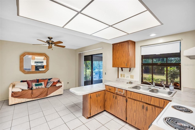 kitchen with light tile patterned flooring, sink, a skylight, range with electric stovetop, and kitchen peninsula