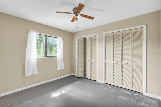 unfurnished bedroom featuring two closets, concrete floors, and ceiling fan