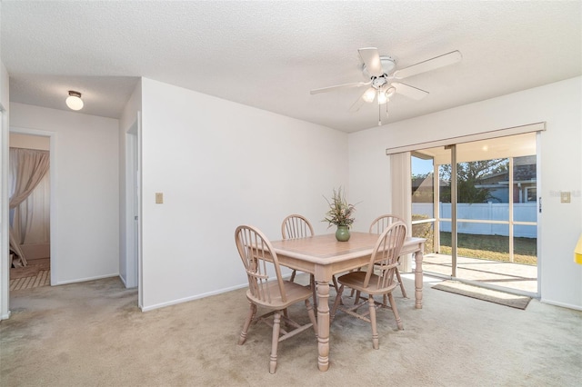 dining space featuring a textured ceiling, light carpet, and ceiling fan