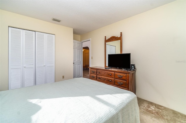 bedroom featuring a textured ceiling, light carpet, and a closet