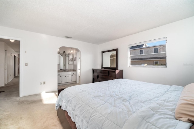 bedroom featuring sink, a textured ceiling, and light colored carpet