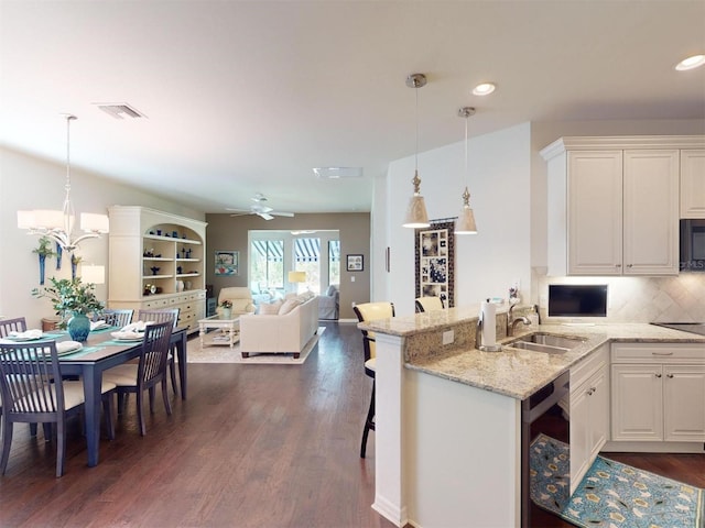 kitchen with white cabinetry, sink, a breakfast bar, and decorative light fixtures