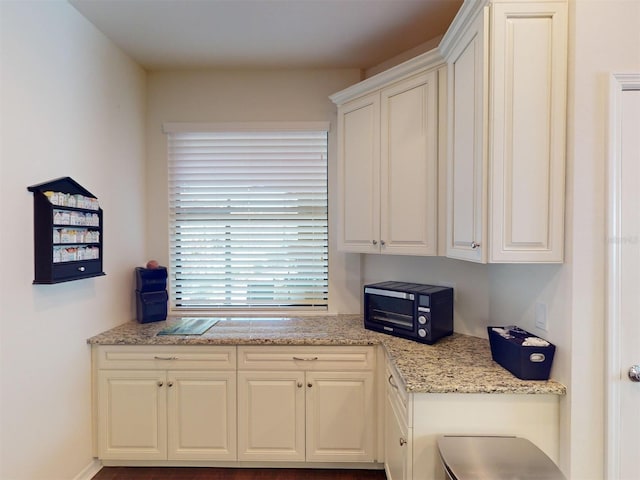 kitchen featuring light stone counters and white cabinets