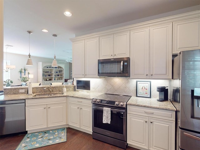 kitchen featuring sink, backsplash, stainless steel appliances, light stone countertops, and decorative light fixtures