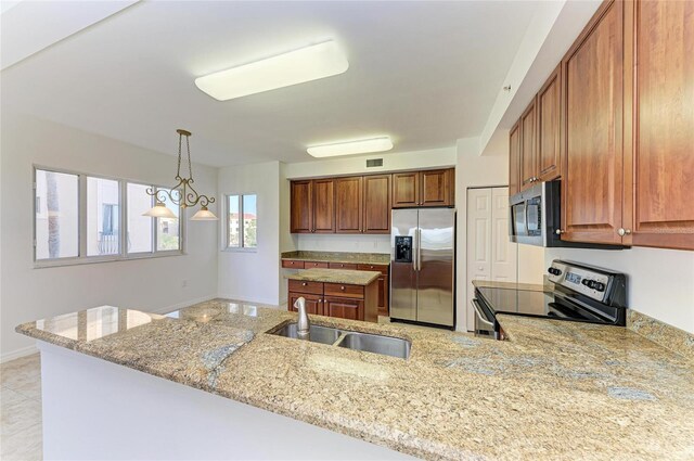 kitchen with appliances with stainless steel finishes, kitchen peninsula, sink, and light stone countertops