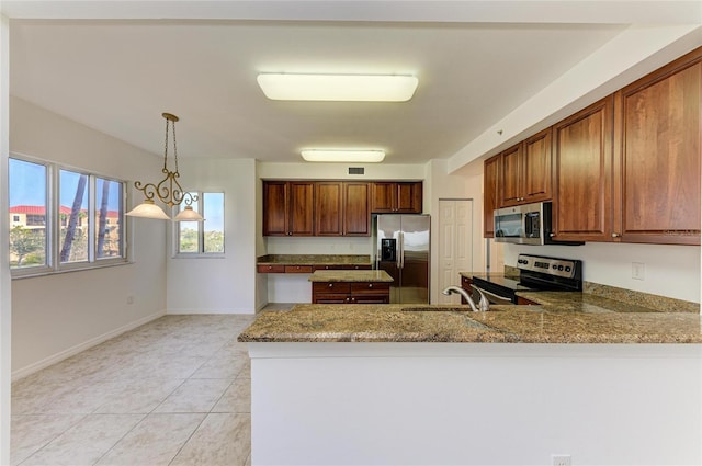 kitchen featuring light stone countertops, appliances with stainless steel finishes, sink, and decorative light fixtures