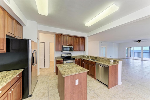 kitchen featuring sink, light stone counters, a center island, kitchen peninsula, and stainless steel appliances