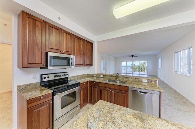 kitchen featuring ceiling fan, appliances with stainless steel finishes, light stone countertops, and sink