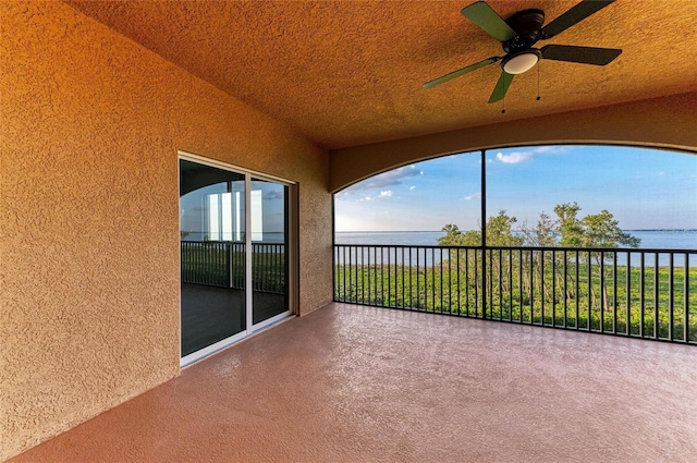 unfurnished sunroom with ceiling fan and a water view