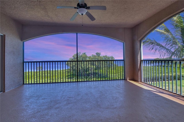 unfurnished sunroom with a water view and ceiling fan