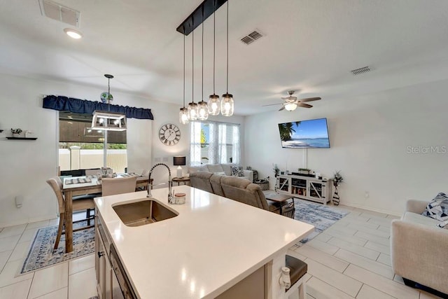 kitchen featuring sink, hanging light fixtures, a kitchen island with sink, light tile patterned floors, and ceiling fan