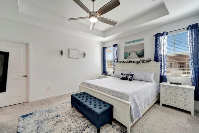 bedroom featuring a tray ceiling, light colored carpet, and ceiling fan