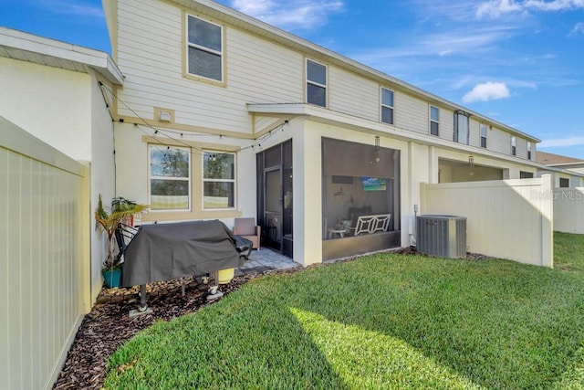 rear view of property with a yard, central AC unit, and a sunroom